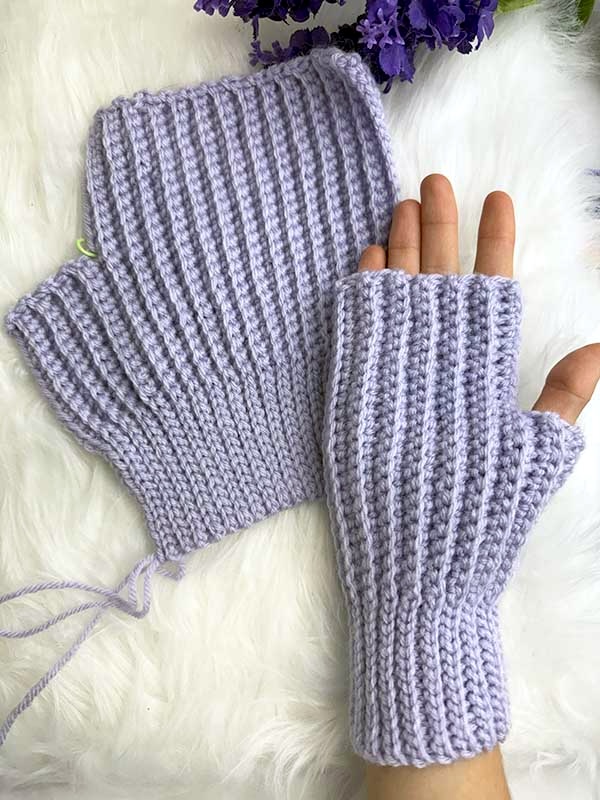 crochet ribbed fingerless glove - one finished glove is finished and is shown on the female hand. The second one is unfinished and lays flat on the table